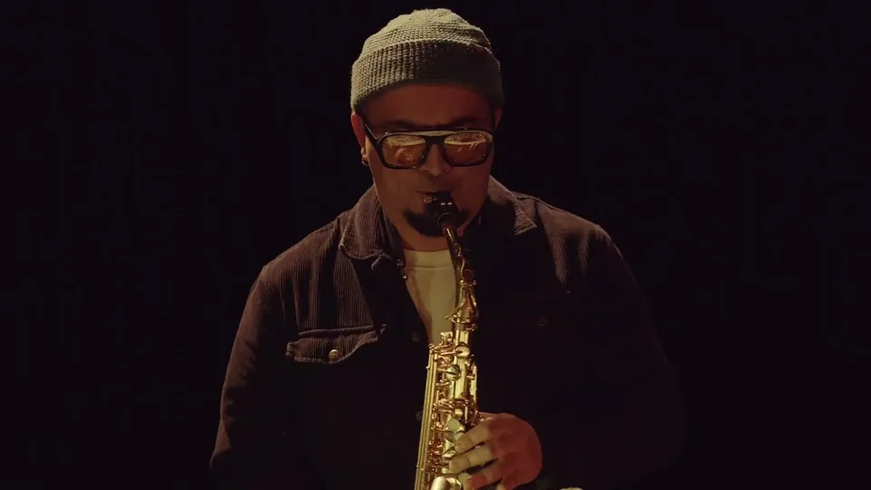 César Vidal playing saxophone against a black background in alea V.
